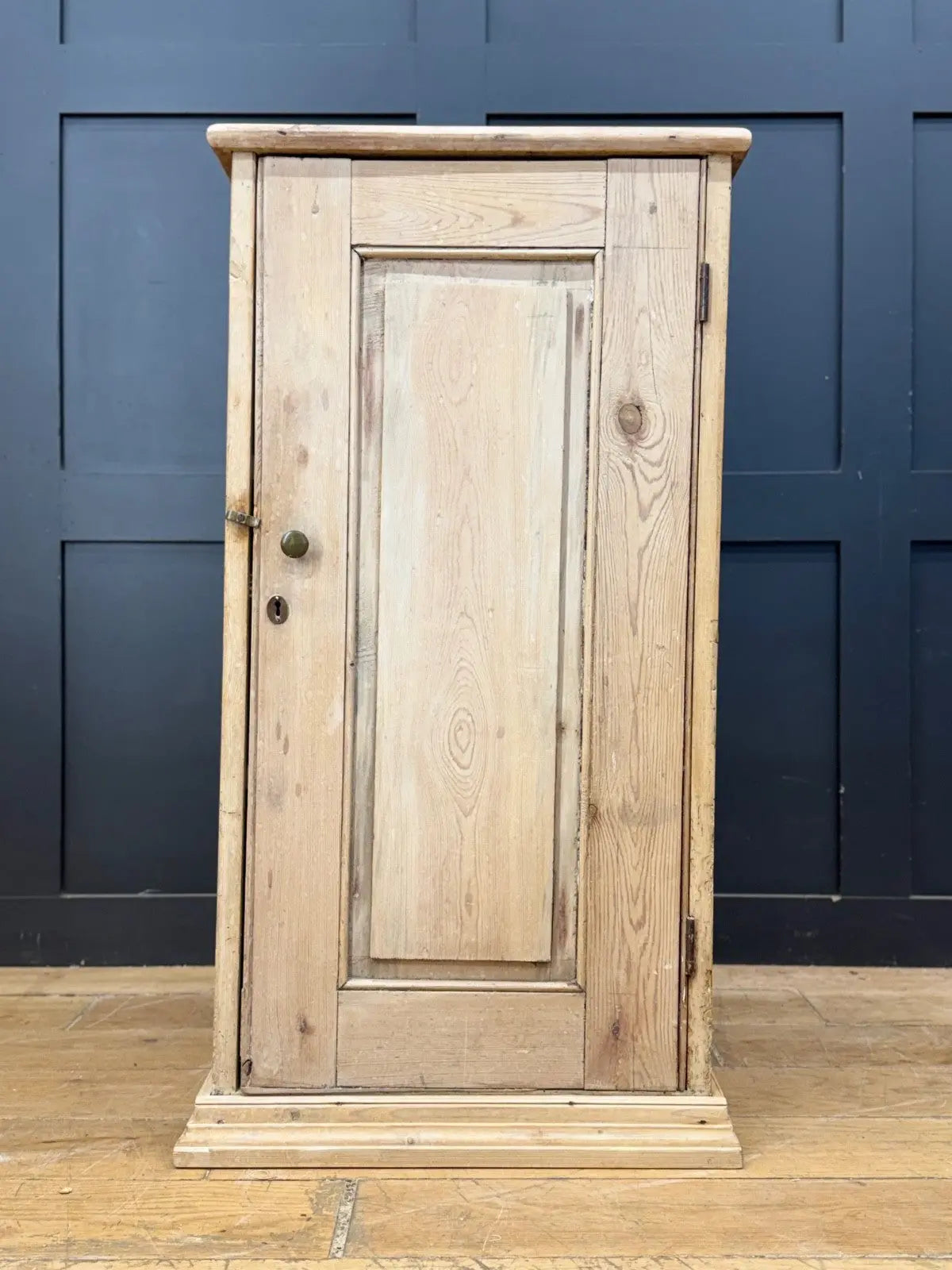 Antique beige pine cupboard with stripped finish, brass knob, and painted interior.