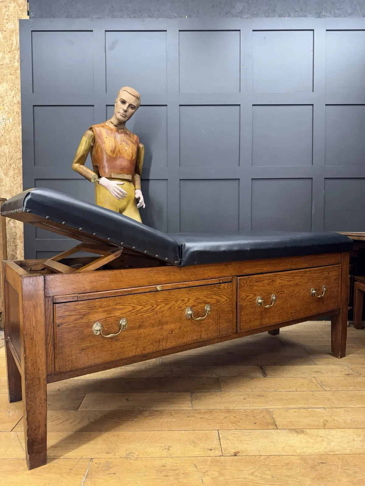 Harris black chaise longue with oak frame, padded Rexine seat, and original maker's plaque.