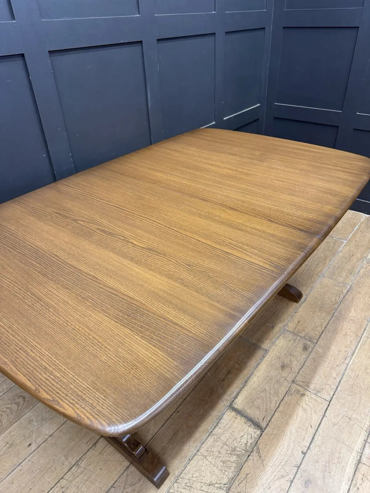 Ercol brown extending dining table with solid elm top and three individual extension leaves.
