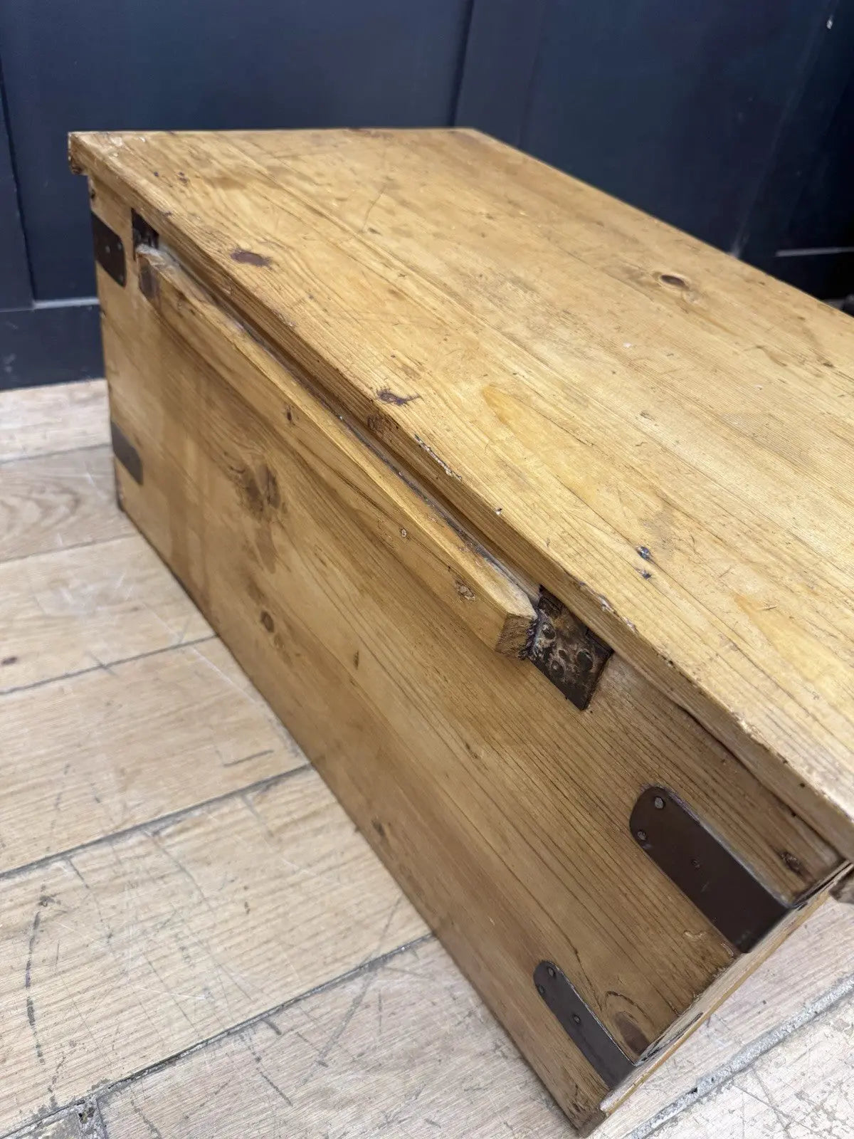 Vintage pine coffee table brown with natural grain and dark metal corner brackets.