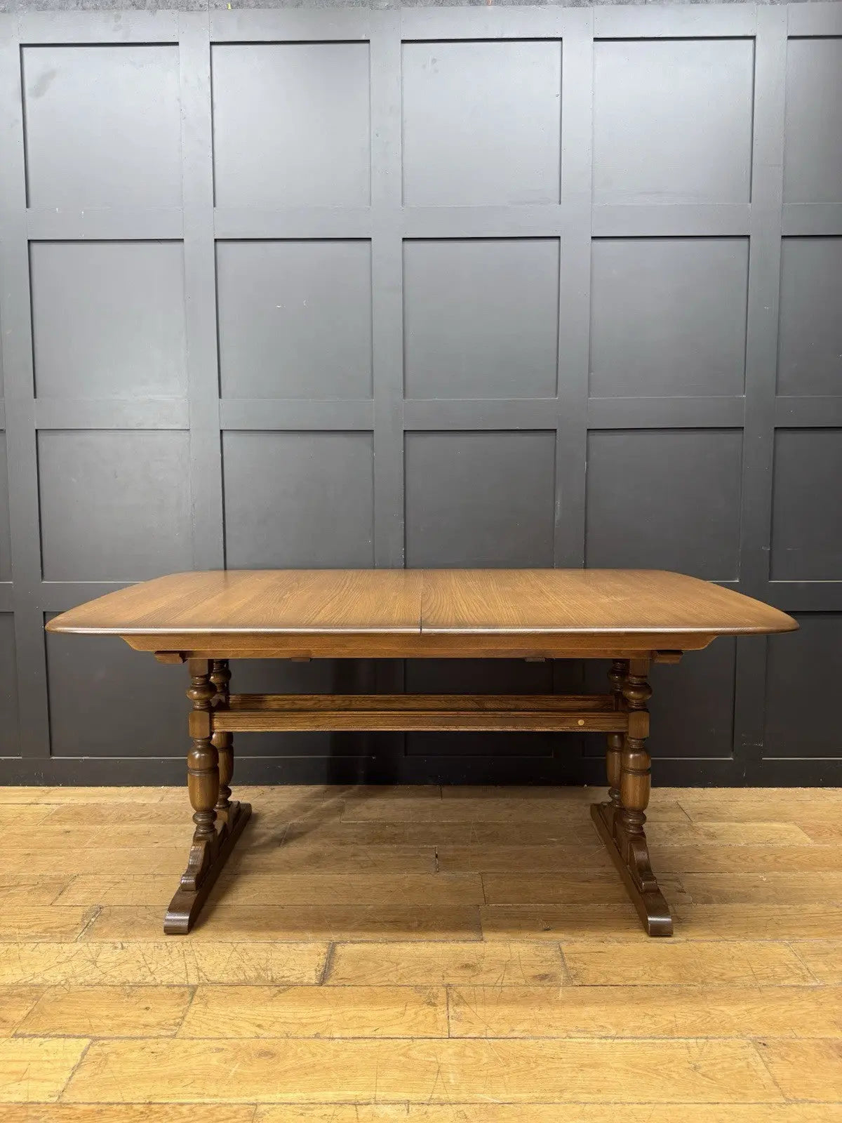 Ercol brown extending dining table with solid elm top and three individual extension leaves.