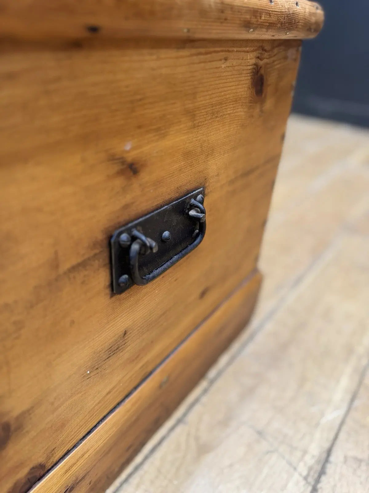 Antique pine hope chest with honey-coloured finish, iron handles, and dovetailed joints.