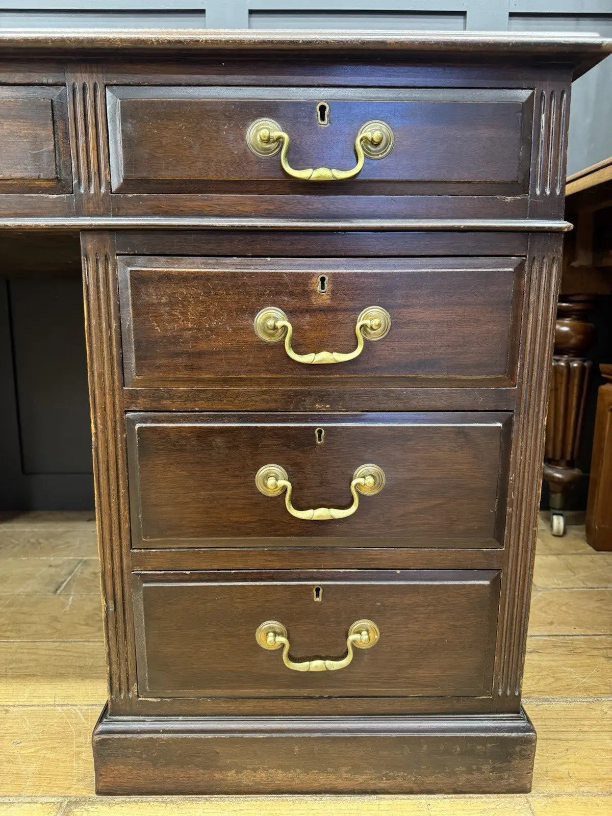 Twin antique mahogany writing desk with red leather top and brass swan-neck handles.