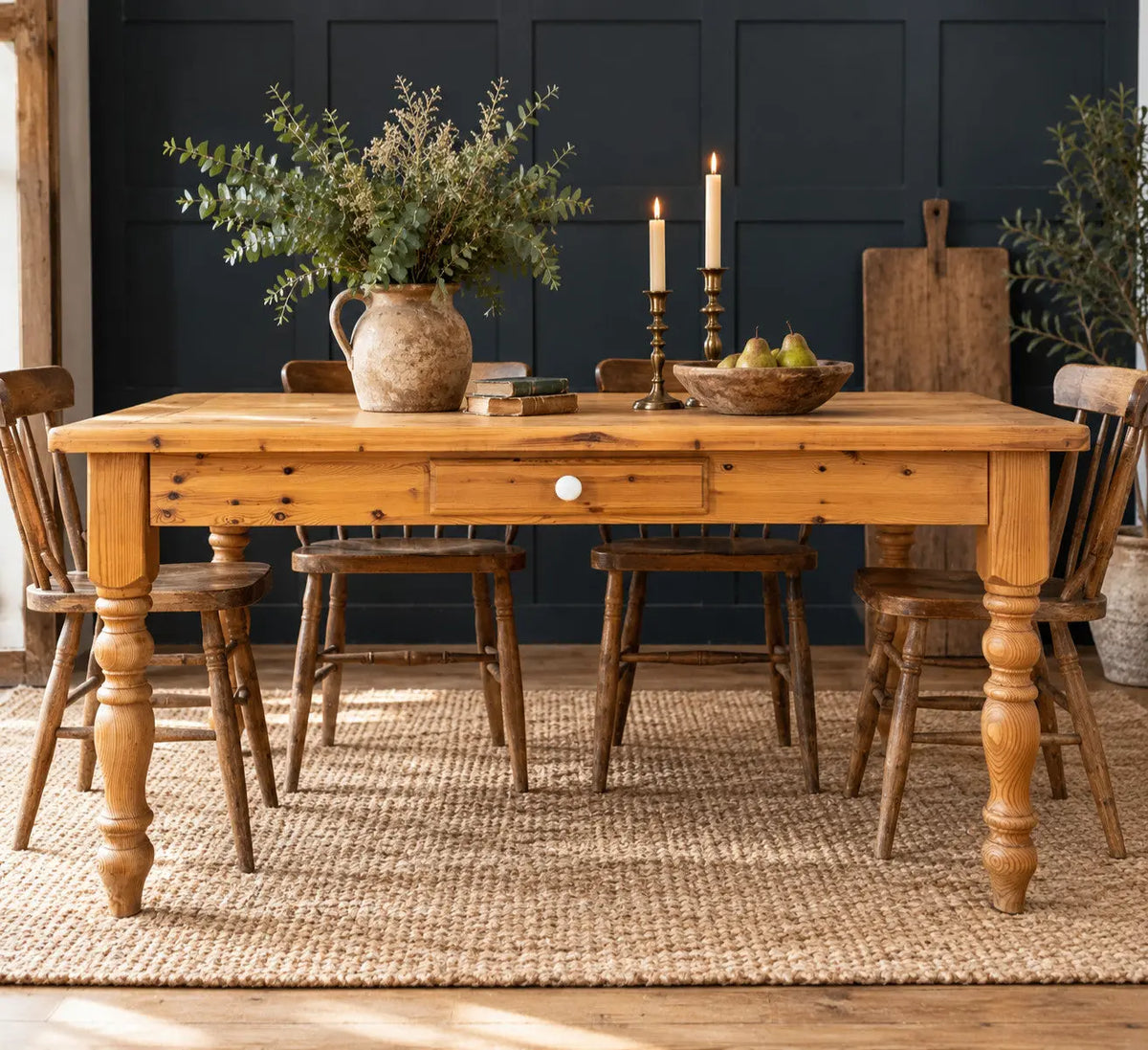 Vintage brown farmhouse dining table with turned legs and central drawer featuring white ceramic knob.