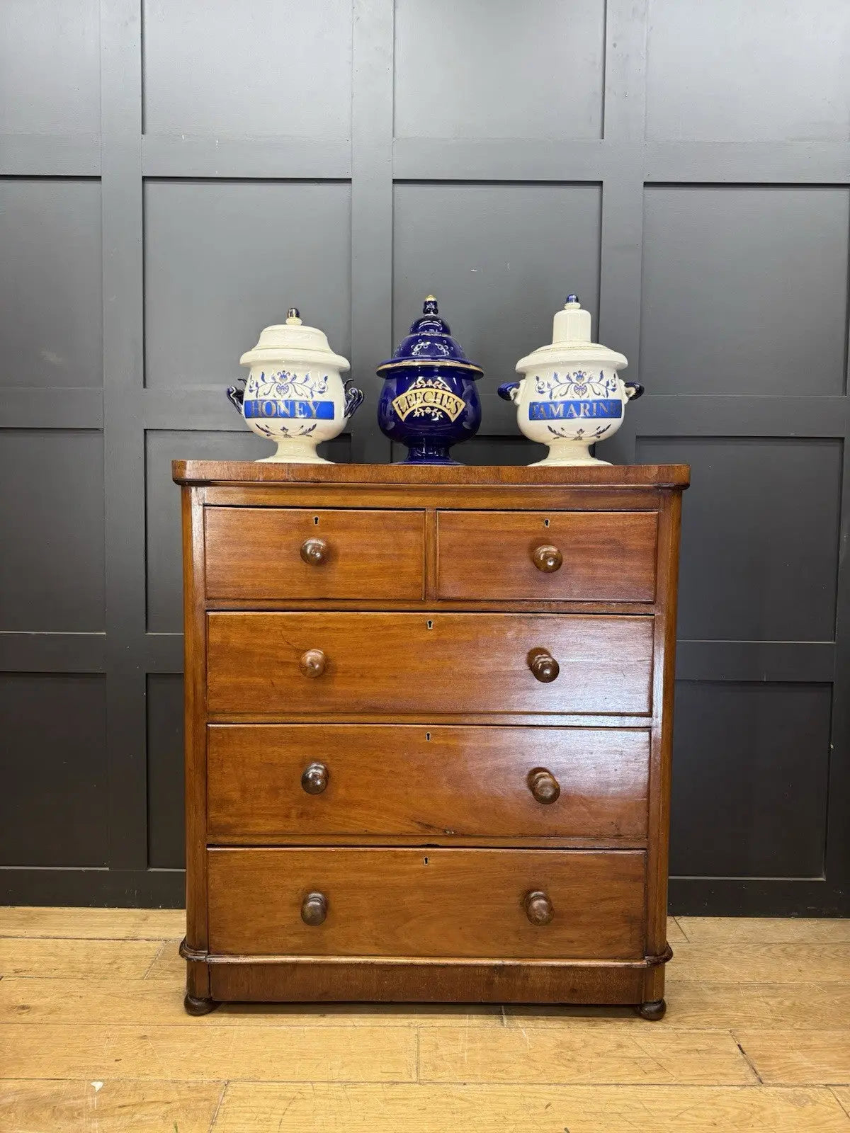 Antique brown mahogany chest of drawers with rounded corners and wooden knob handles.