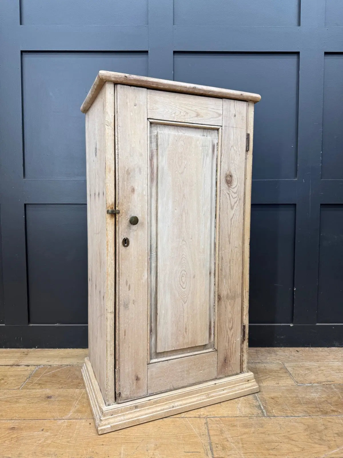 Antique beige pine cupboard with stripped finish, brass knob, and painted interior.