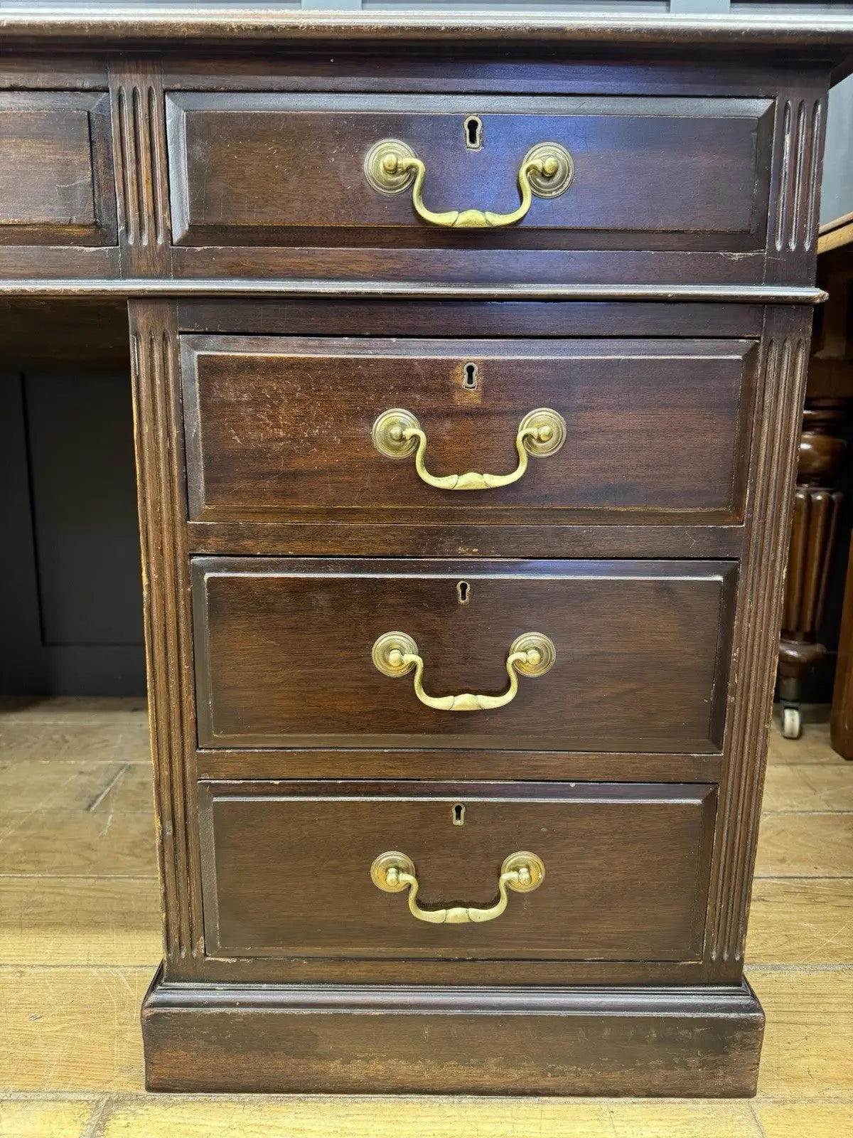 Twin antique mahogany writing desk with red leather top and brass swan-neck handles.