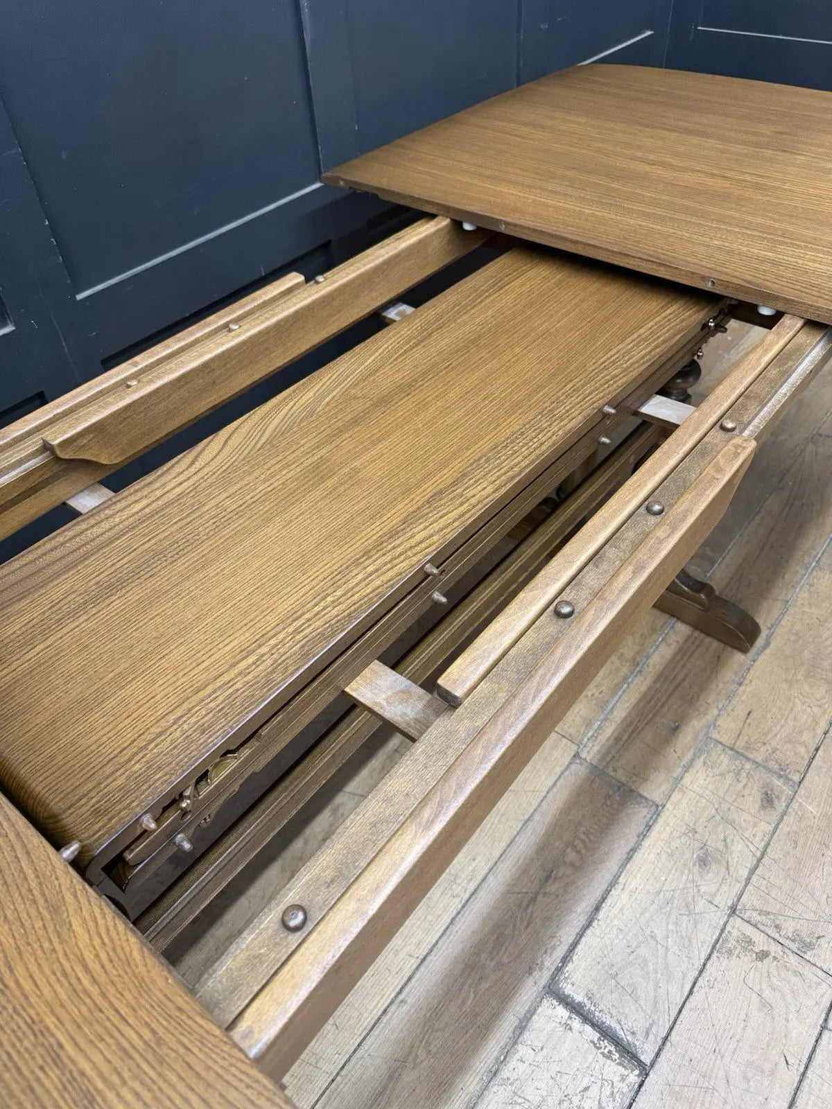 Ercol brown extending dining table with solid elm top and three individual extension leaves.