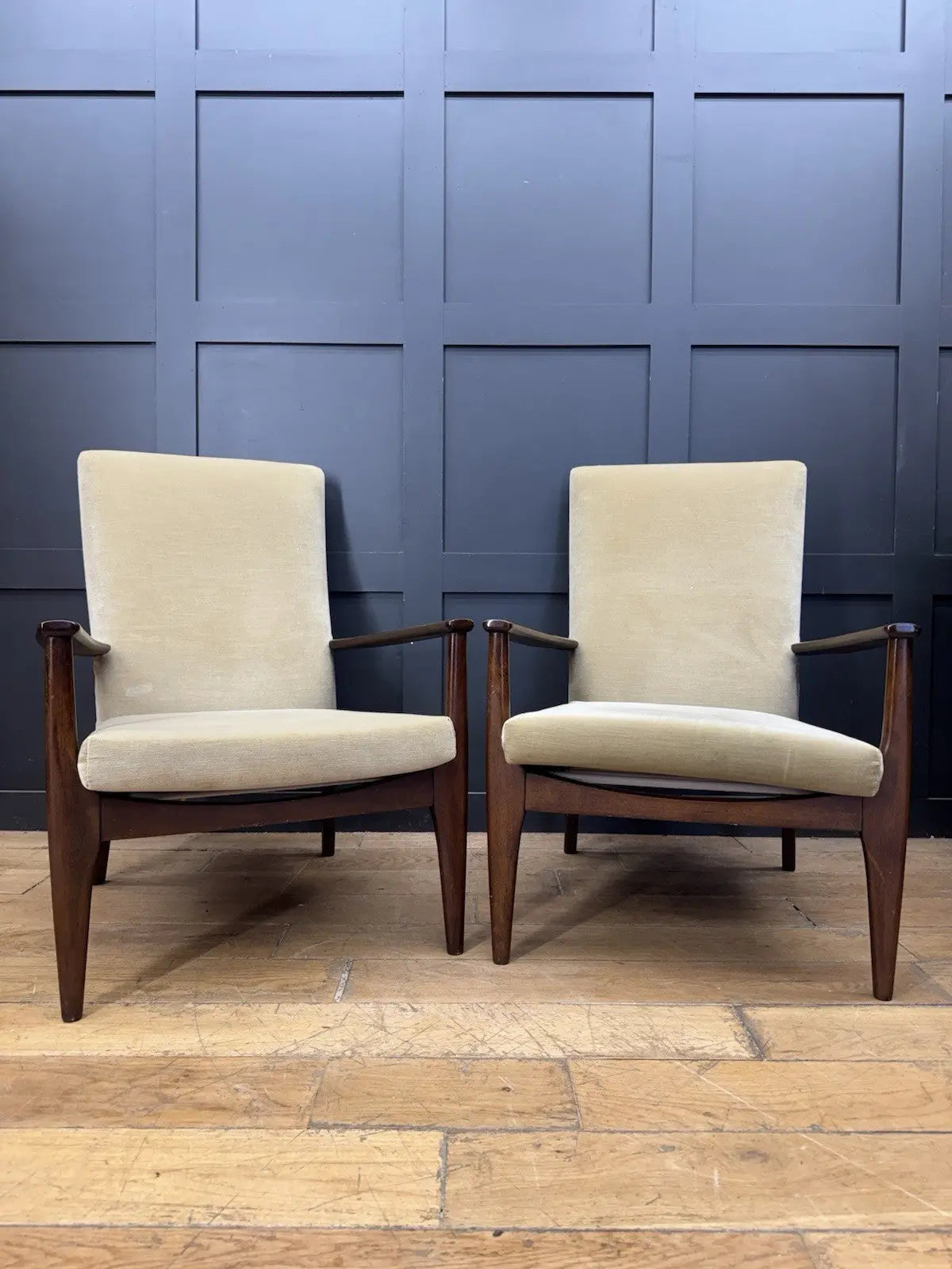 Parker Knoll cream armchairs with sculpted wooden arms and tapered legs, vintage mid-century design.