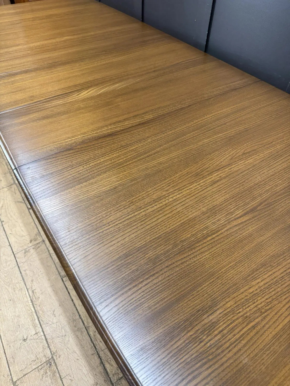 Ercol brown extending dining table with solid elm top and three individual extension leaves.