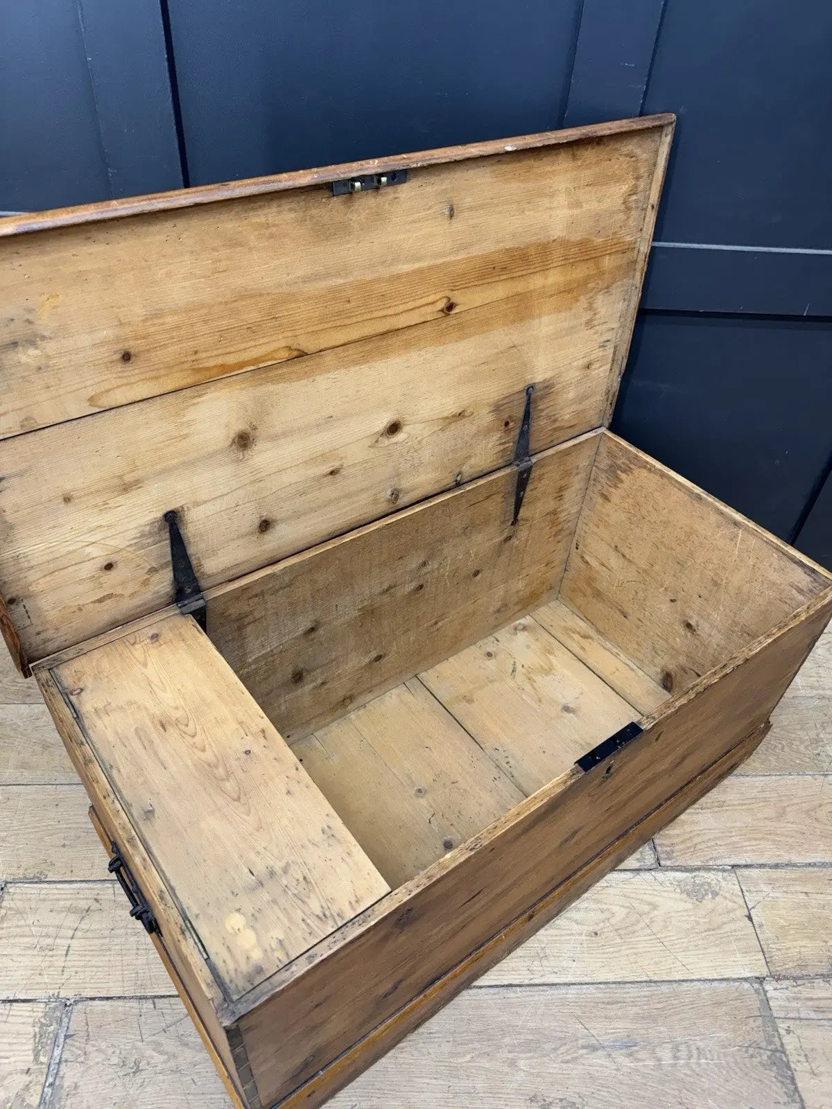 Antique pine hope chest with honey-coloured finish, iron handles, and dovetailed joints.
