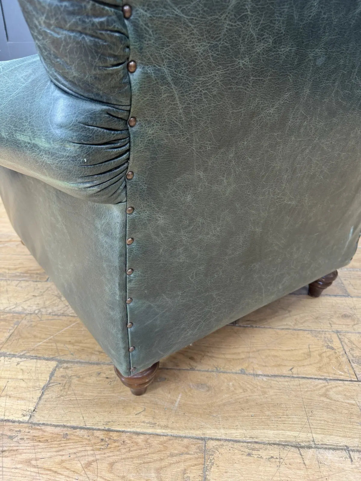Tetrad green leather armchair with gathered detailing, twisted piping, and original manufacturer's label.