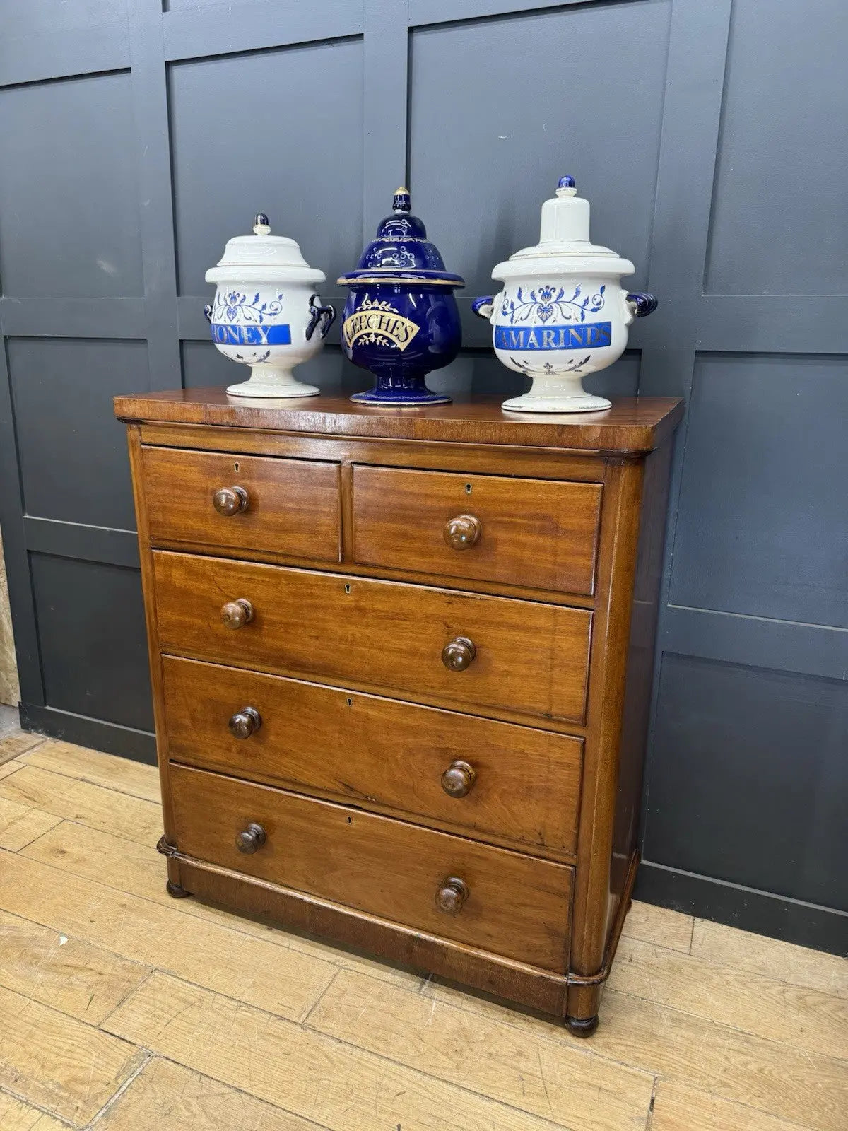 Antique brown mahogany chest of drawers with rounded corners and wooden knob handles.