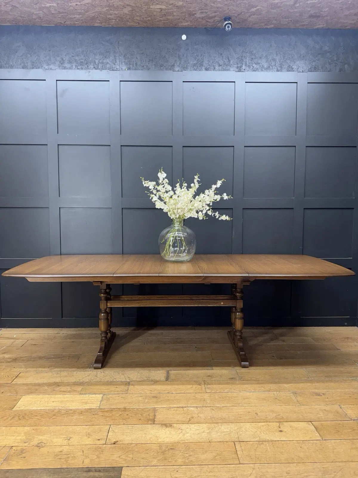 Ercol brown extending dining table with solid elm top and three individual extension leaves.
