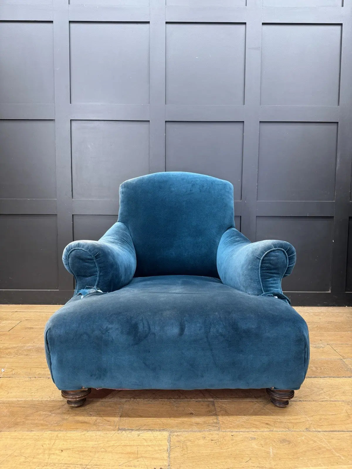Antique blue velvet armchair with curved back, scroll arms, and stamped 'P' on frame.