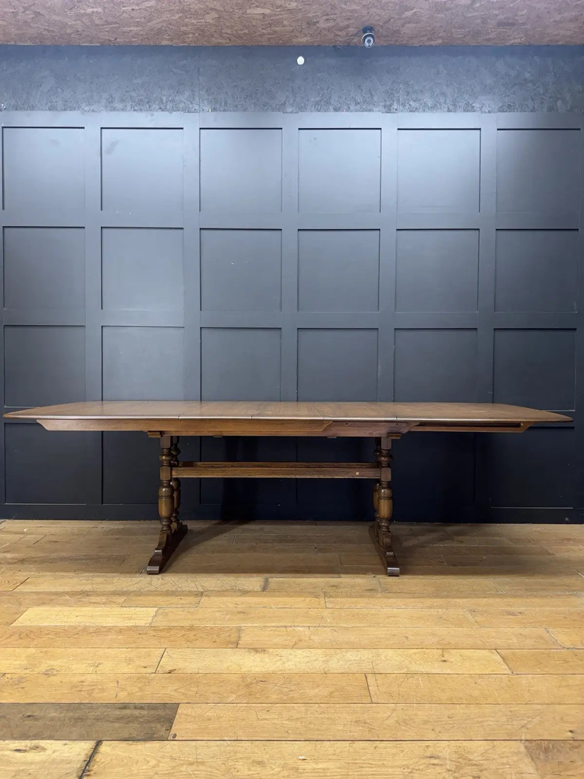 Ercol brown extending dining table with solid elm top and three individual extension leaves.