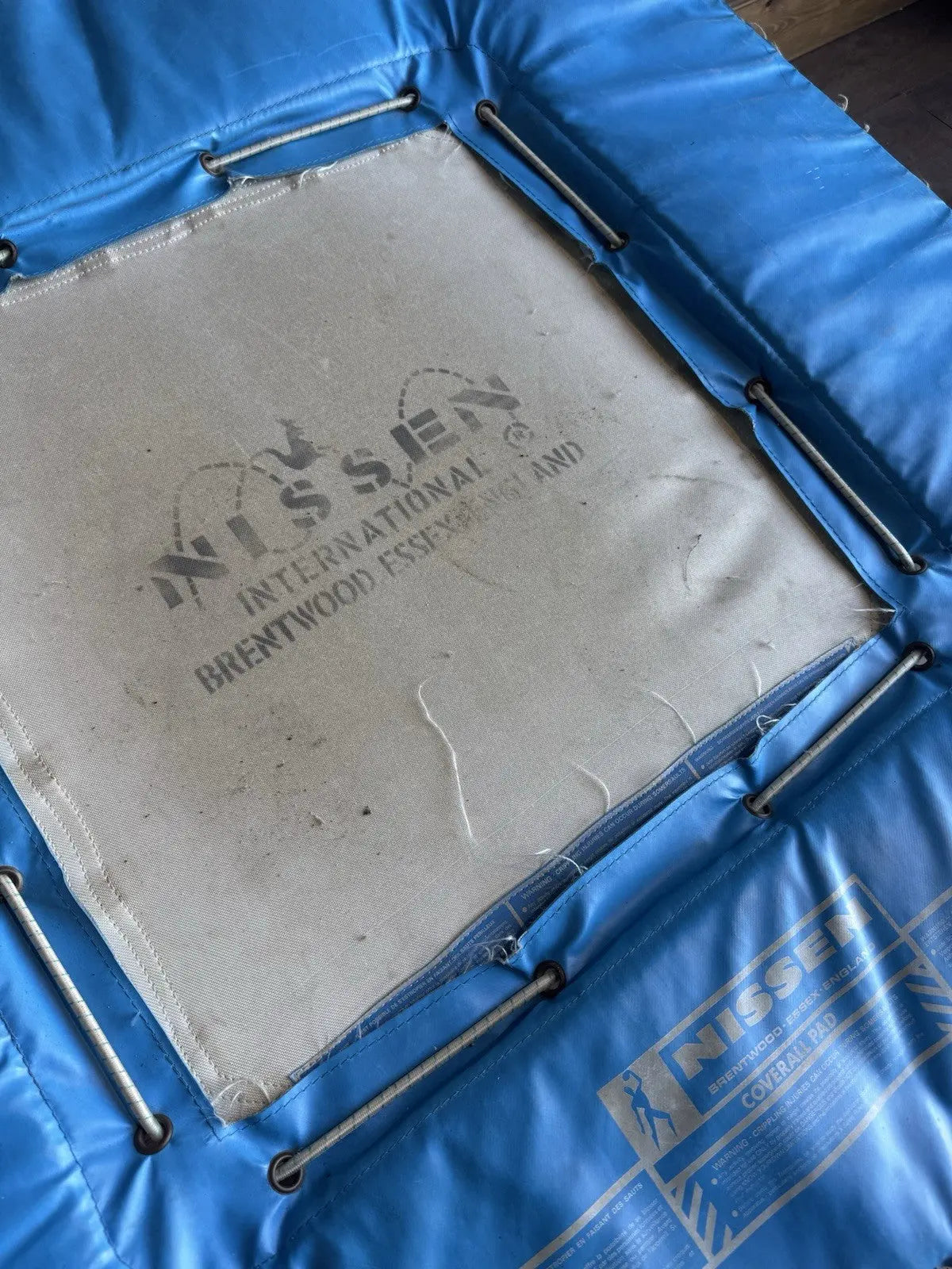 Rebounder black and blue gymnastics trampette with Nissen International logo and woven jumping bed.