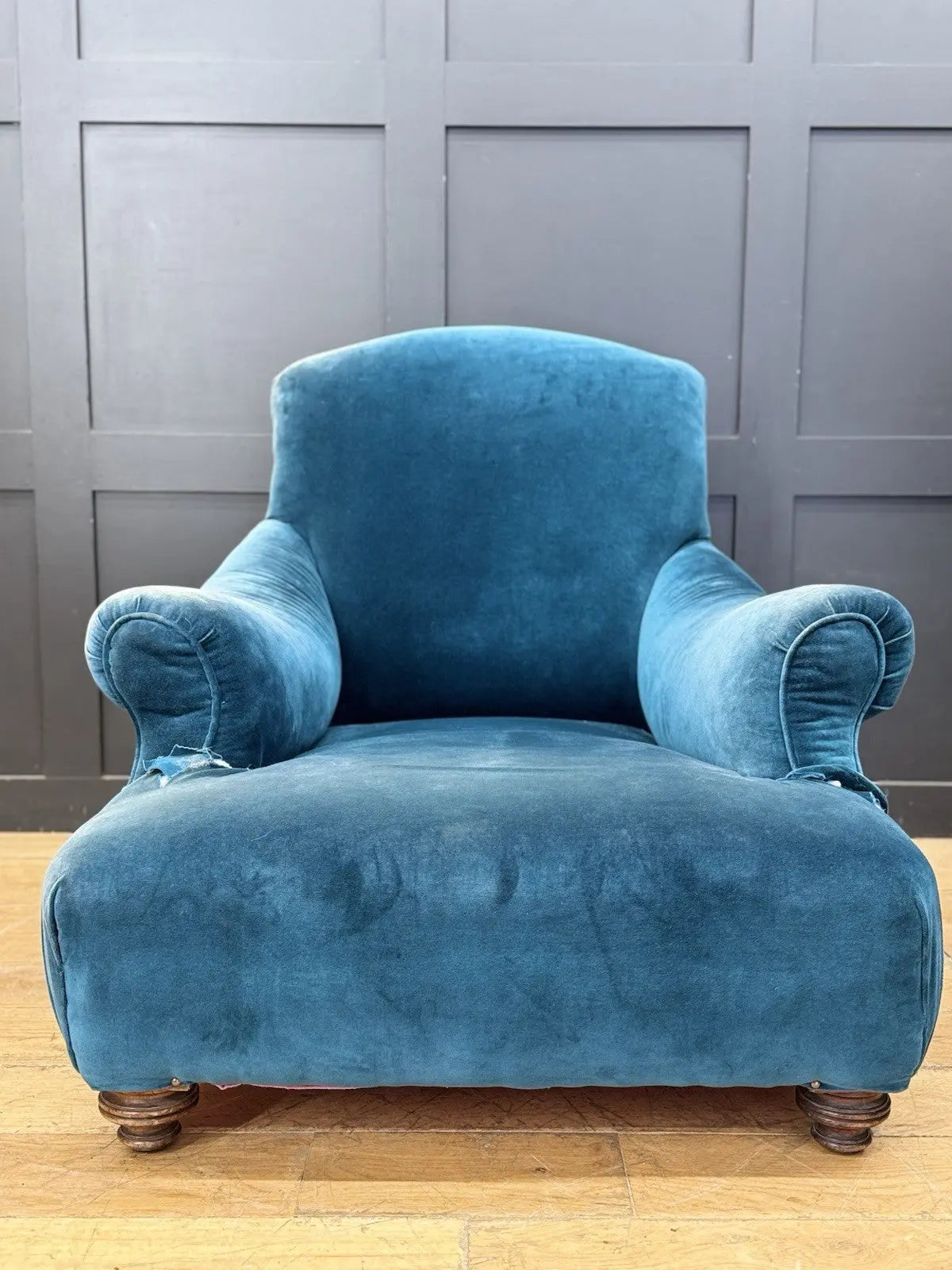 Antique blue velvet armchair with curved back, scroll arms, and stamped 'P' on frame.