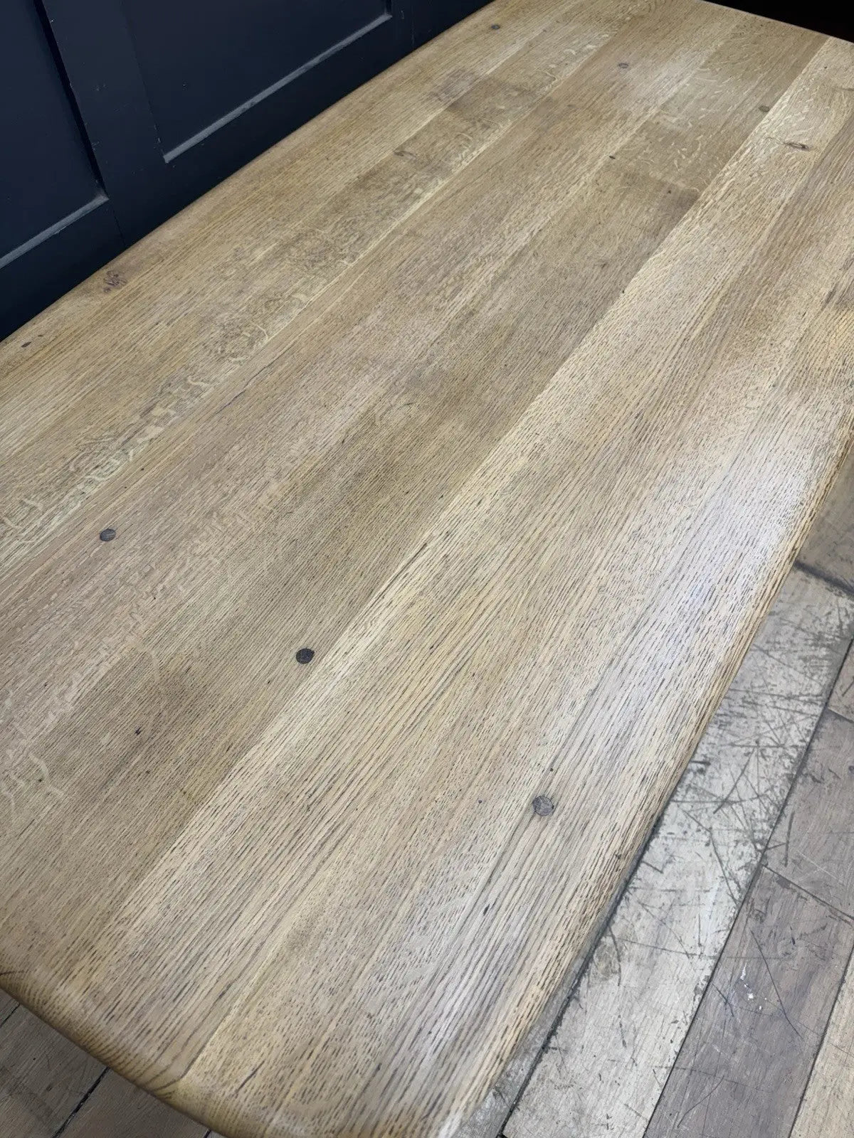 Ercol brown oak refectory dining table with natural wood grain and traditional trestle base.