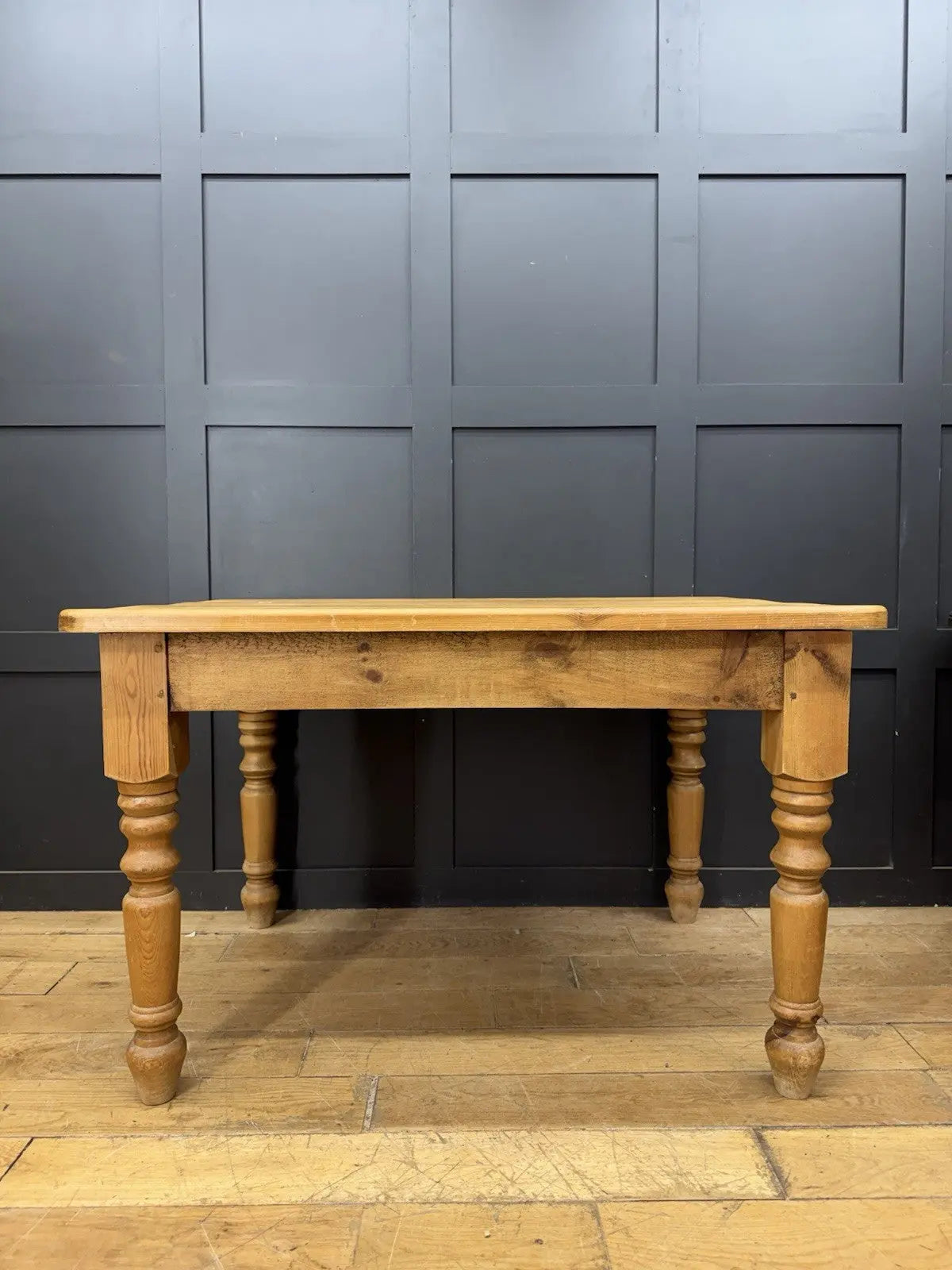 Pine farmhouse dining table brown rectangular top with turned legs and natural grain.