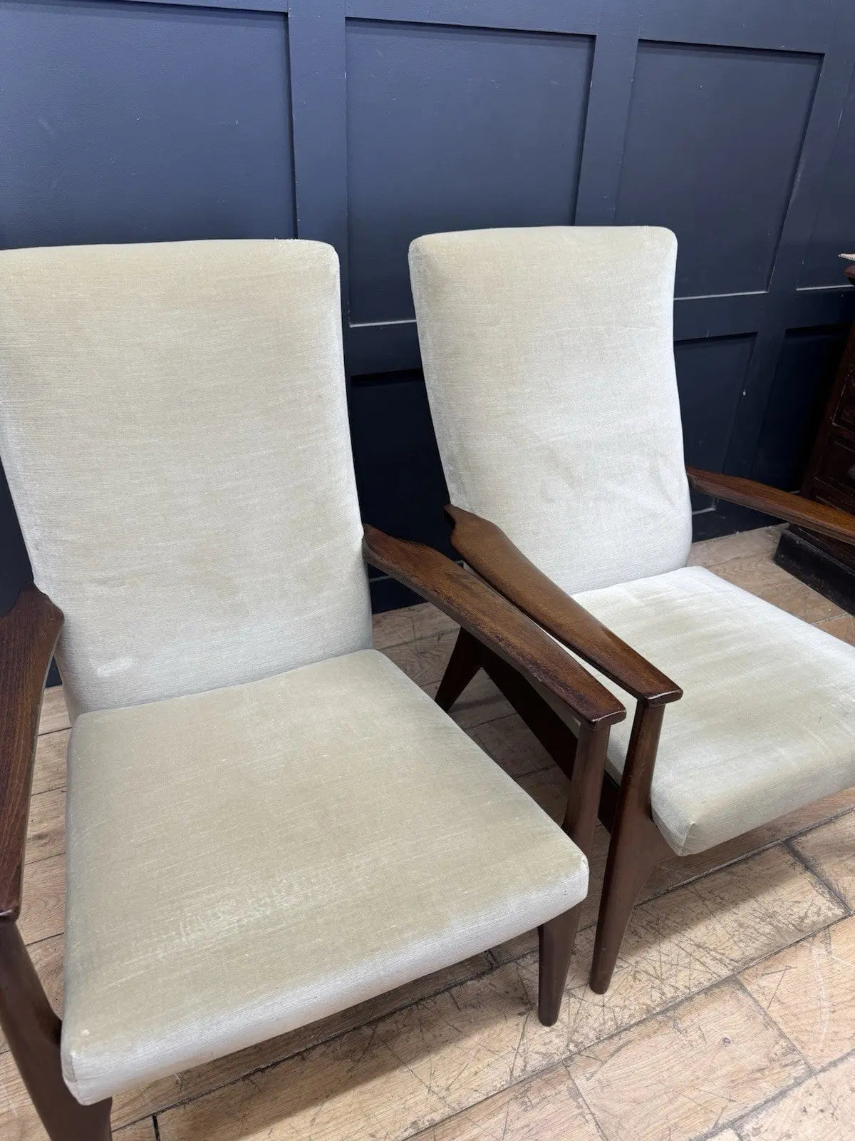 Parker Knoll cream armchairs with sculpted wooden arms and tapered legs, vintage mid-century design.