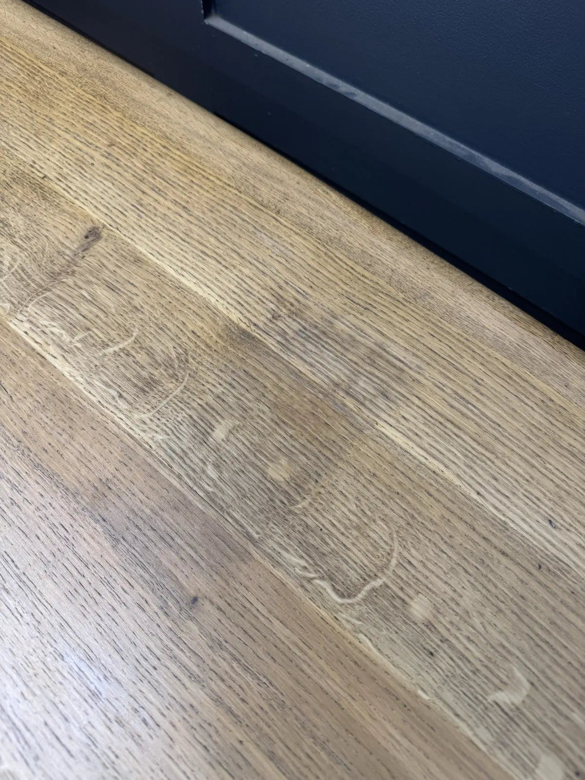 Ercol brown oak refectory dining table with natural wood grain and traditional trestle base.