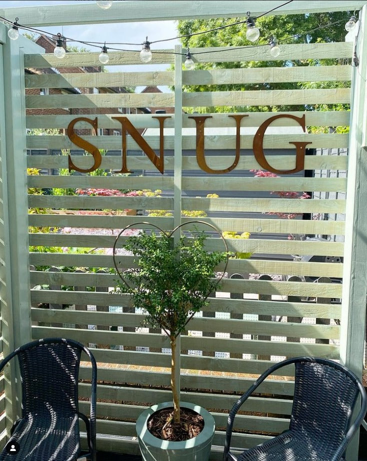 12" tall rusty metal lettering displayed on a fence spelling out SNUG