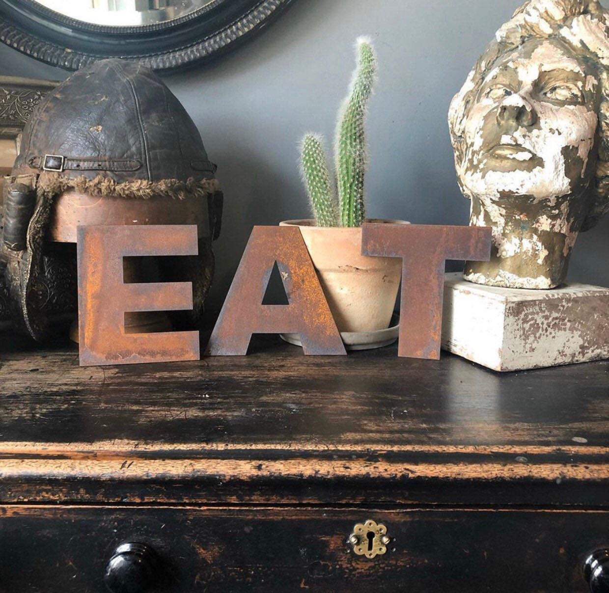 5" tall rusty metal industrial style lettering spelling out EAT