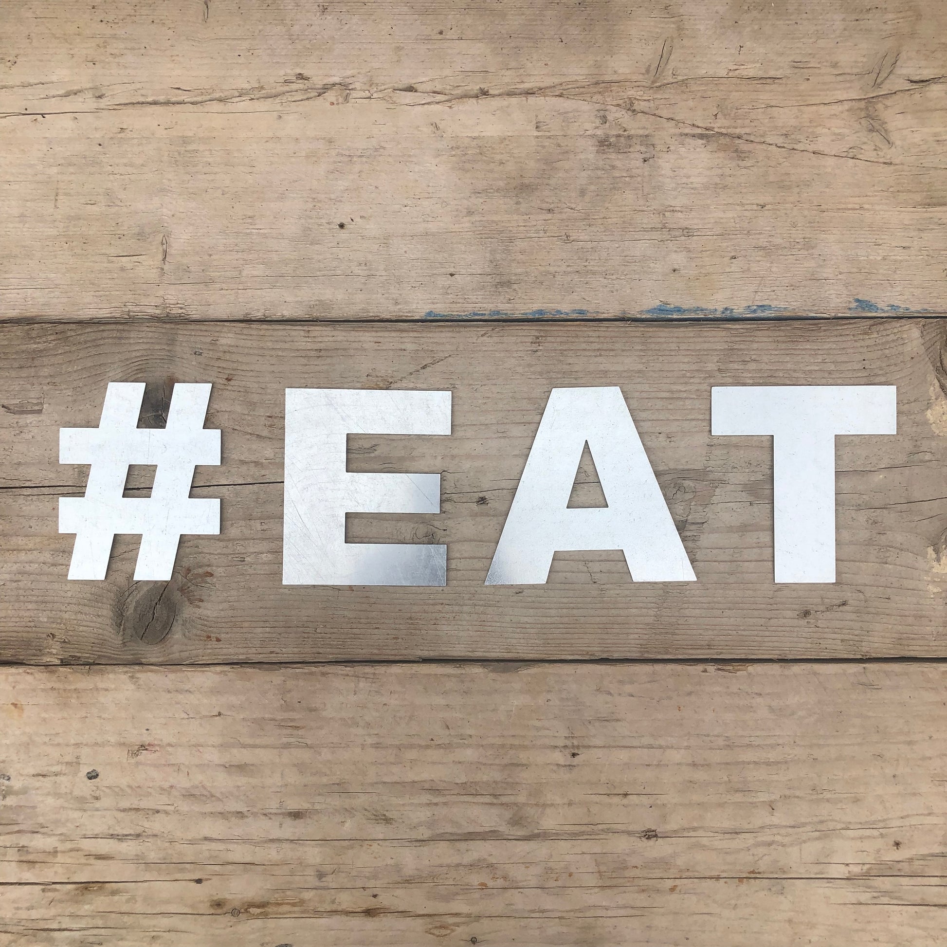 Galvanized steel fat font lettering spelling out #EAT