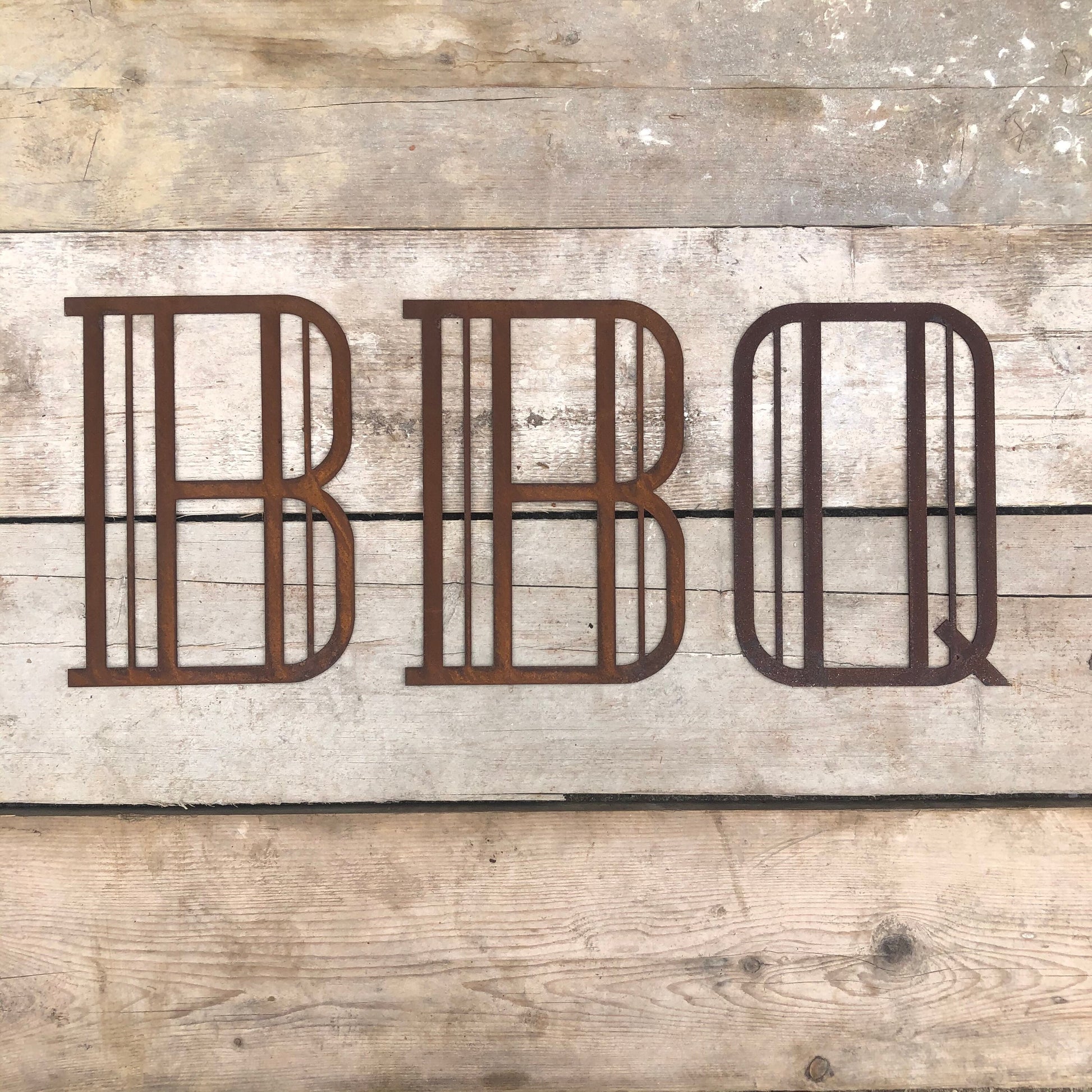 Rusty metal art deco style lettering spelling out BBQ